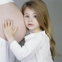 Девочка стоит у живота беременной мамы